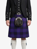 Person wearing a black jacket, purple plaid kilt, and white knee-high socks on a white background