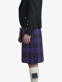 Person wearing a black jacket and purple plaid kilt on a white background