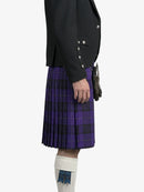 Person wearing a black jacket and purple plaid kilt on a white background