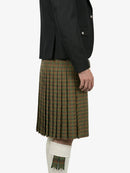 Person wearing a black jacket and plaid kilt on a white background