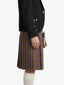 Person wearing a black jacket and plaid kilt on a white background