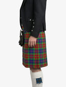 Person wearing a black jacket and colorful plaid kilt on a white background