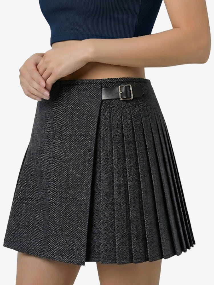 Person wearing a pleated skirt with a belt on a plain background