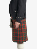 Person wearing a dark jacket and red plaid kilt on a white background