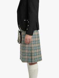 Person wearing a black jacket and plaid kilt on a white background