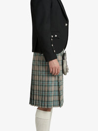 Person wearing a black blazer and plaid kilt on a white background