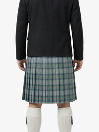 Person wearing a black jacket and plaid kilt on a white background
