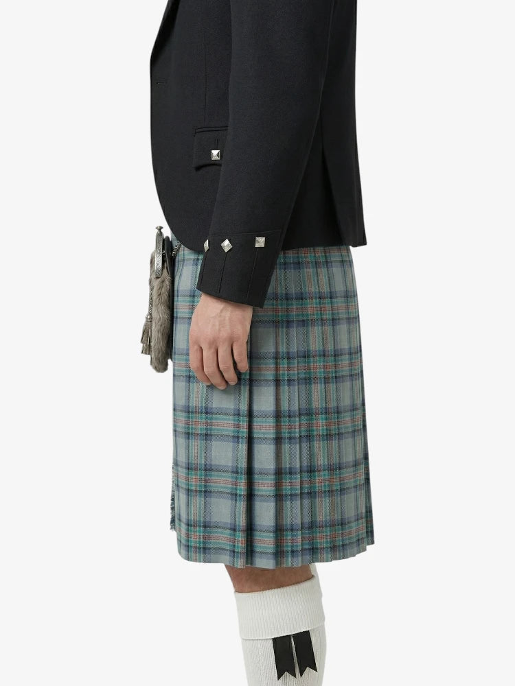 Person wearing a black blazer and plaid kilt on a white background