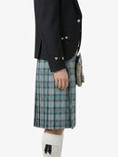 Person wearing a black jacket and plaid kilt on a white background