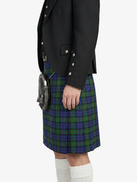 Person wearing a black blazer and plaid kilt on a white background