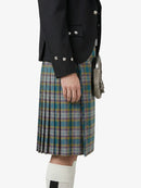 Person wearing a black jacket and plaid kilt on a white background