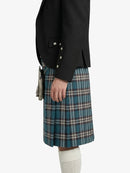 Person wearing a black blazer and blue plaid kilt on a white background