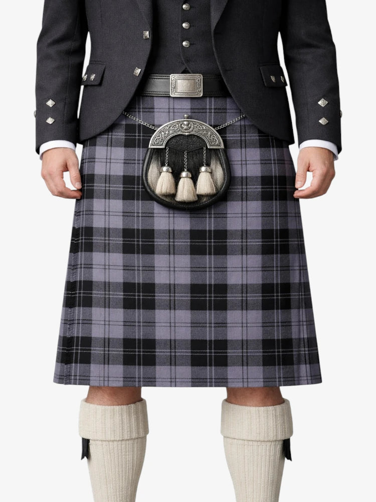 Person wearing a traditional Scottish kilt with a patterned belt and jacket on a white background