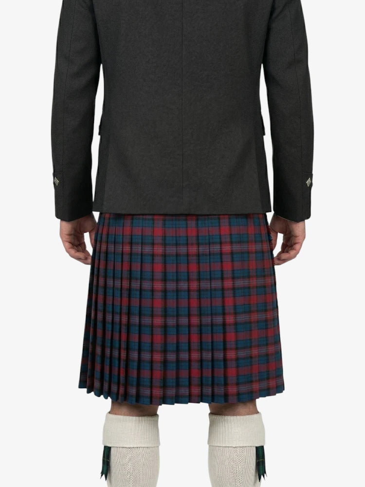 Person wearing a dark jacket and red plaid kilt on a white background