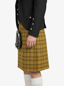 Person wearing a black jacket and yellow plaid kilt on a white background