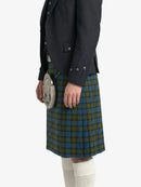 Person wearing a dark jacket and green plaid kilt on a white background