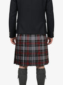 Person wearing a black jacket and red plaid kilt on a white background