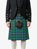 Person wearing a black jacket and green plaid kilt on a white background