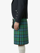 Person wearing a dark jacket and green plaid kilt on a white background