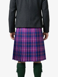Person wearing a purple plaid kilt with a gray jacket on a white background