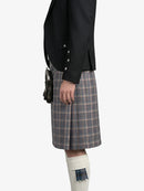 Person wearing a black jacket and plaid kilt on a white background