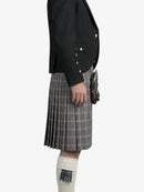Person wearing a black jacket and plaid kilt on a white background
