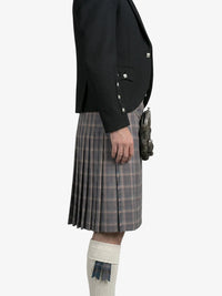Person wearing a black jacket and plaid kilt on a white background
