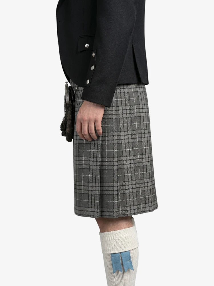 Person wearing a black jacket and gray plaid kilt on a white background