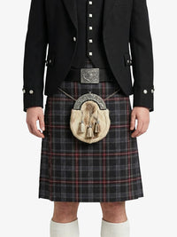 Person wearing a traditional Scottish kilt with a black jacket and white shirt on a white background