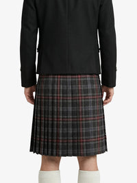 Person wearing a black coat and plaid kilt on a white background