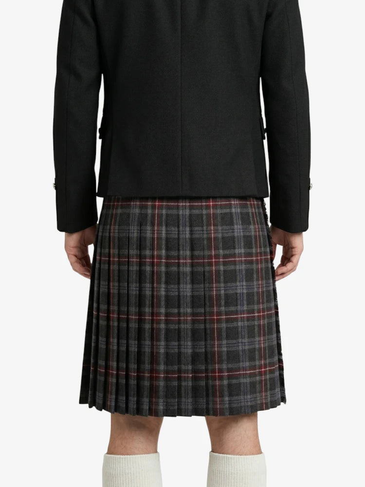 Person wearing a black coat and plaid kilt on a white background