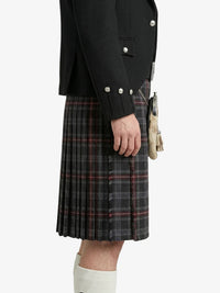 Person wearing a black jacket with pearl buttons and a plaid kilt on a white background