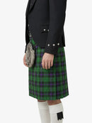 Person wearing a green plaid kilt with a black jacket on a white background