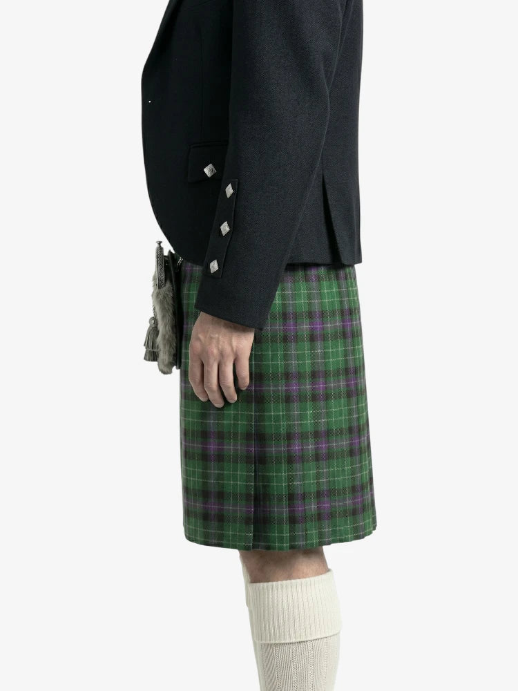 Person wearing a black jacket and green plaid kilt on a white background