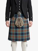 Person wearing a traditional Scottish kilt with a tartan pattern on a white background