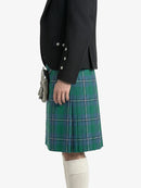 Person wearing a black jacket and green plaid kilt on a white background
