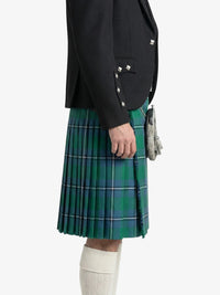 Person wearing a black jacket and green plaid kilt on a white background