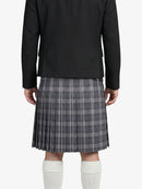 Person wearing a black blazer and plaid kilt on a white background