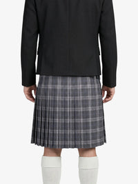 Person wearing a black blazer and plaid kilt on a white background