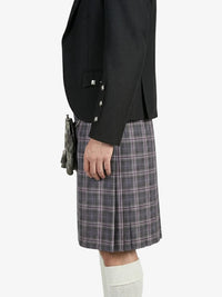 Person wearing a black blazer and plaid kilt on a white background