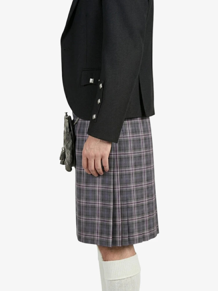Person wearing a black blazer and plaid kilt on a white background