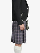 Person wearing a black blazer and plaid kilt on a white background