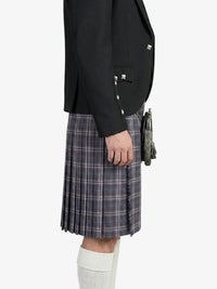Person wearing a black blazer and plaid kilt on a white background