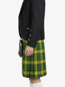 Person wearing a black blazer and green plaid kilt on a white background