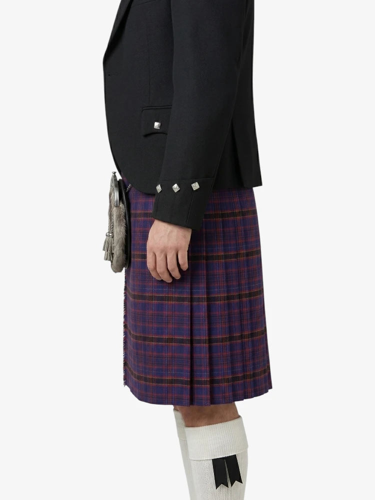 Person wearing a black blazer and red plaid kilt on a white background
