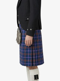 Person wearing a black jacket and blue plaid kilt on a white background