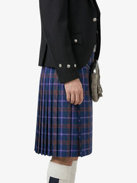 Person wearing a black jacket and blue plaid kilt on a white background
