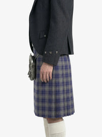 Person wearing a dark gray jacket and blue plaid kilt on a white background