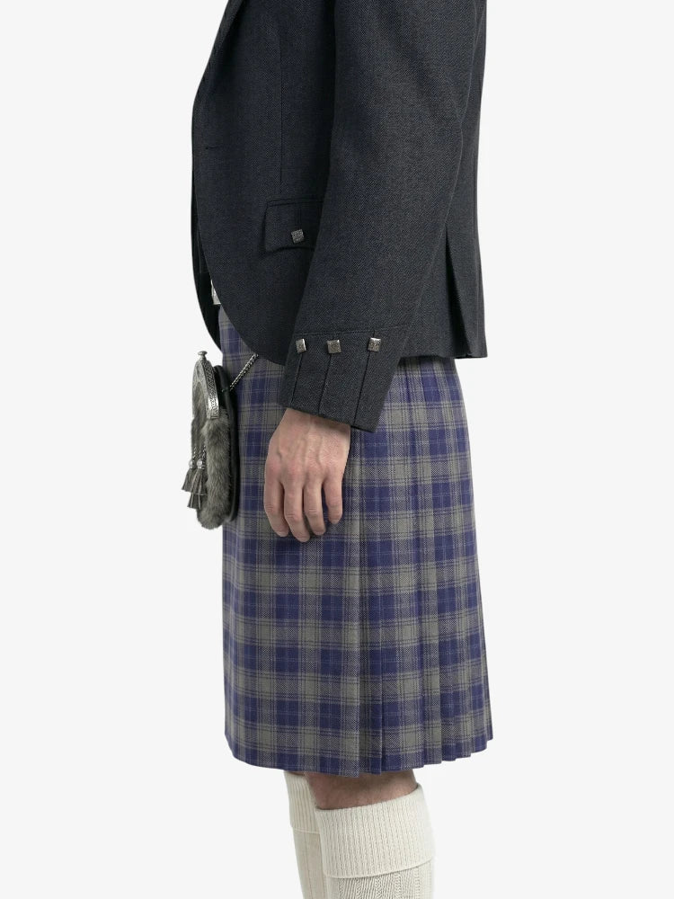 Person wearing a dark gray jacket and blue plaid kilt on a white background
