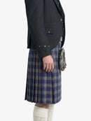 Person wearing a dark gray jacket and blue plaid kilt on a white background